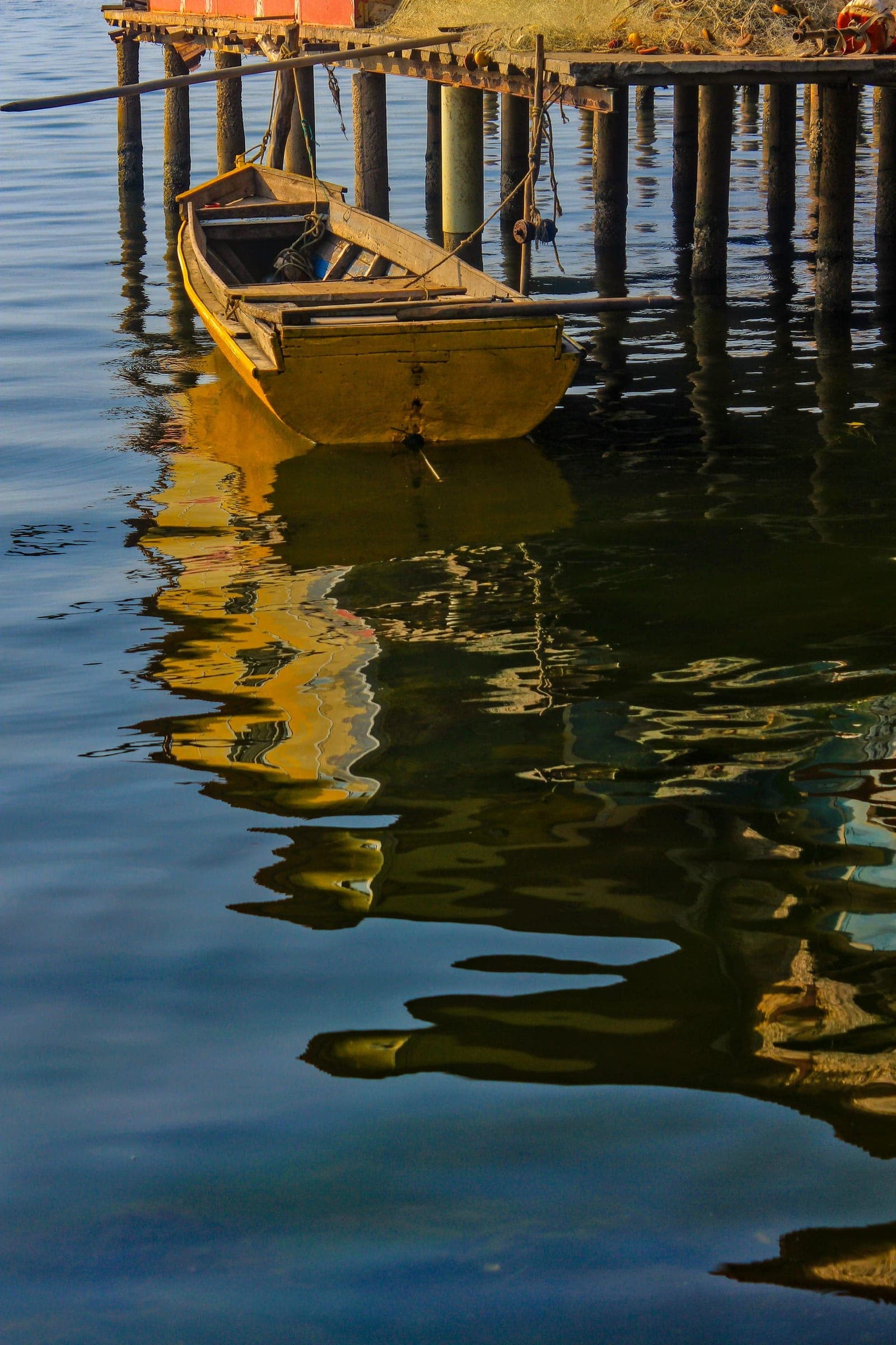 Bote amarrado a un palafito con su reflejo en el agua